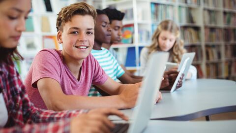 Schülerinnen und Schüler lernen in der Bibliothek mit Laptops Schülerinnen und Schüler lernen in der Bibliothek mit Laptops