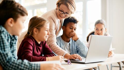 Lehrerin zeigt Kinder in der Grundschule etwas an einem Laptop. Lehrerin zeigt Kinder in der Grundschule etwas an einem Laptop.